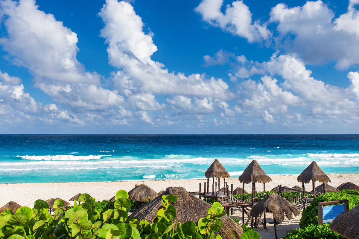 깨끗한-모래-위-방갈로와-멀리-에메랄드빛-바다와-하늘이-끝없이-펼쳐진-멕시코-칸쿤의-해변-풍경